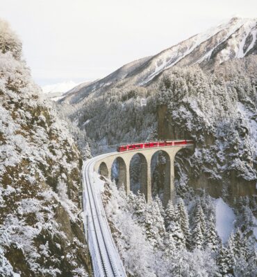 approaching red train across mountains